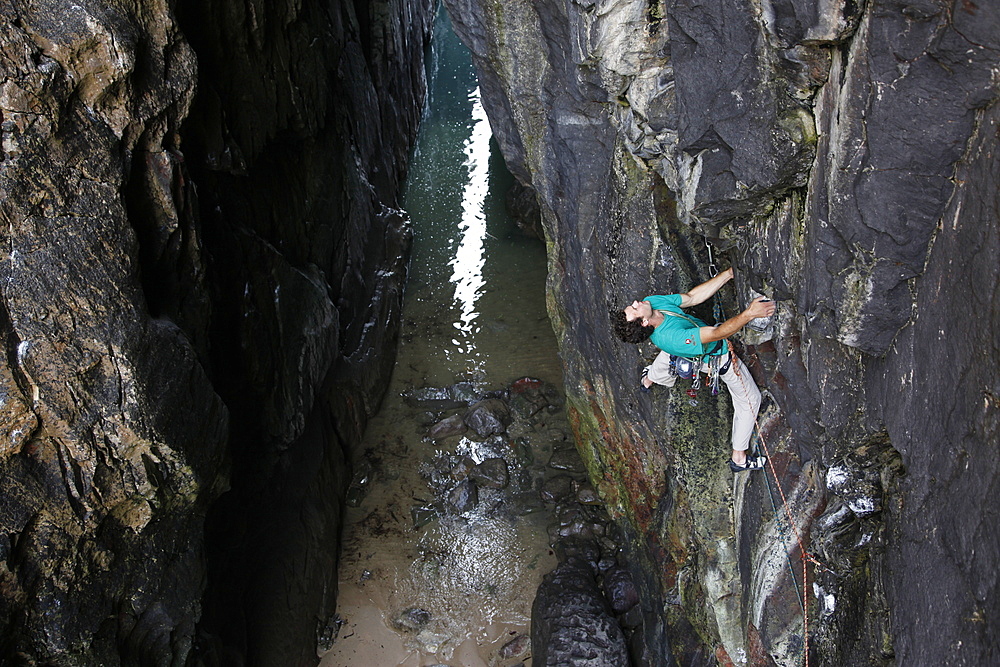 A climber scales cliffs at Huntsman's Leap, Pembrokeshire, Wales, United Kingdom, Europe