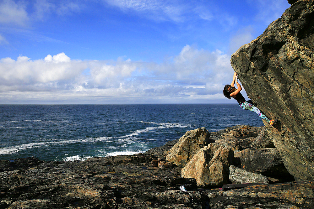 A climber bouldering by the sea near St. Ives, Cornwall, England, United Kingdom, Europe