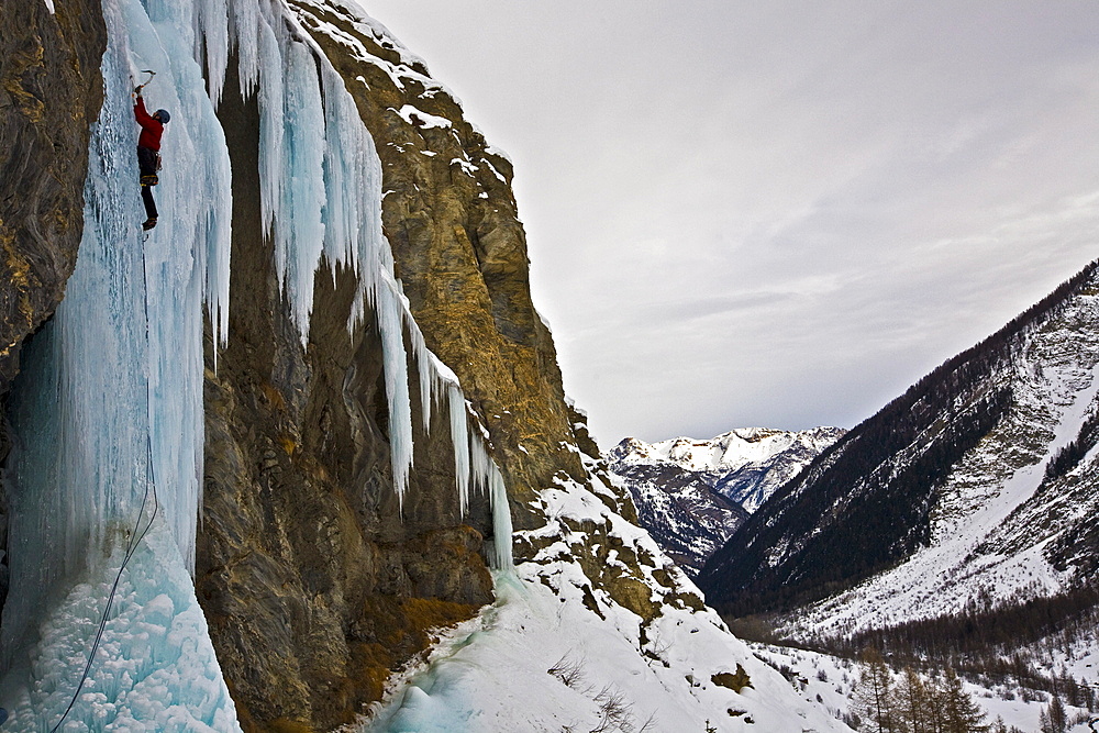 An ice climber ascending a frozen cascade in the Fournel Valley, Ecrins Massif, France, Europe