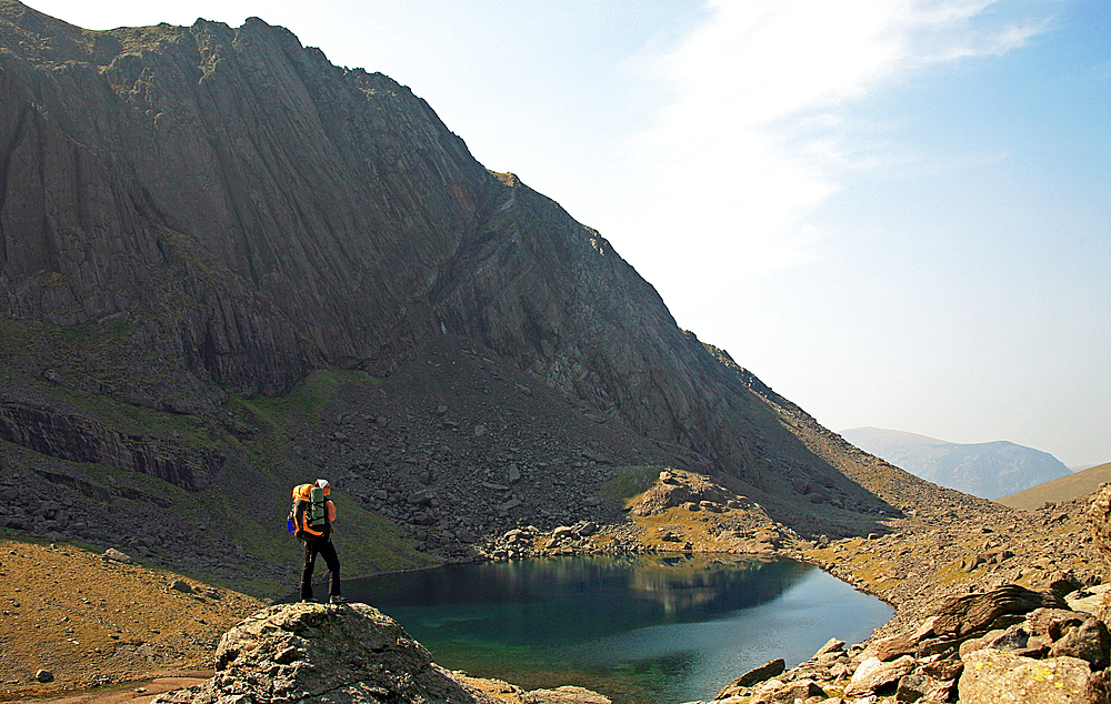 A hiker takes a break above Llyn Du'r Arddu, Snowdonia National Park, North Wales, United Kingdom, Europe