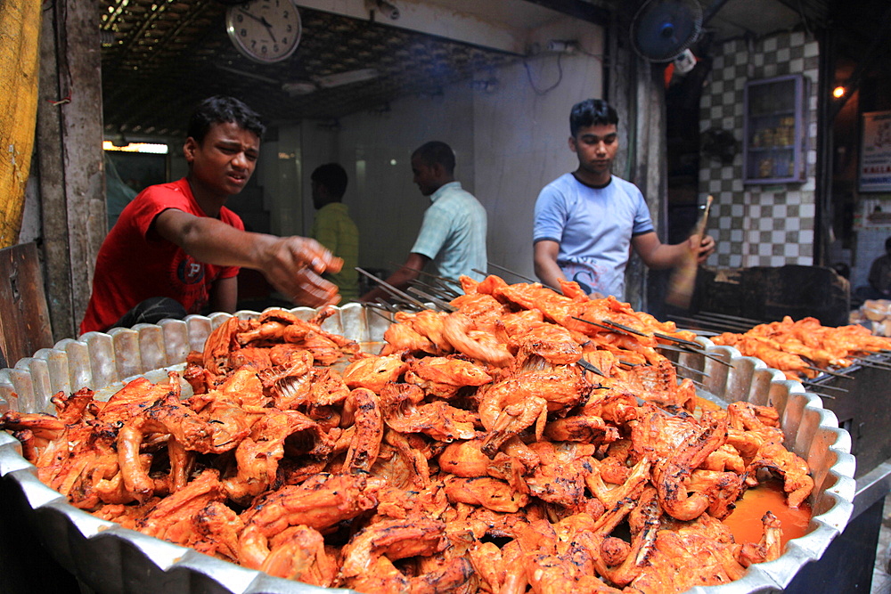 Two tandoor-wallah boys cook tandoori chicken at a street stall in the heart of Old Delhi, Delhi, India, Asia