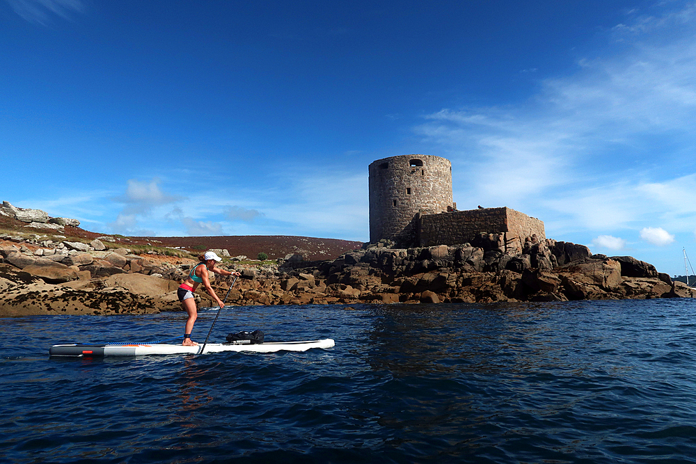 Paddle boarder under Cromwell's Castle, a castle built during the English Civil War on the west coast of Tresco, Isles of Scilly, England, United Kingdom, Europe