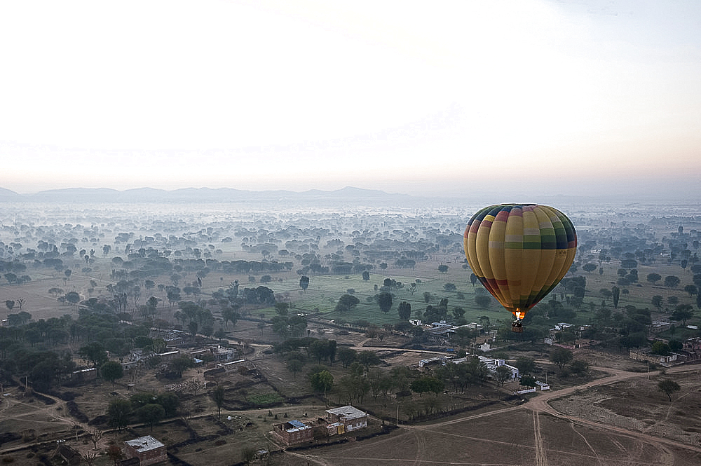 Hot air balloon in the early morning, flying over countryside and the village of Samode, Rajasthan, India, Asia