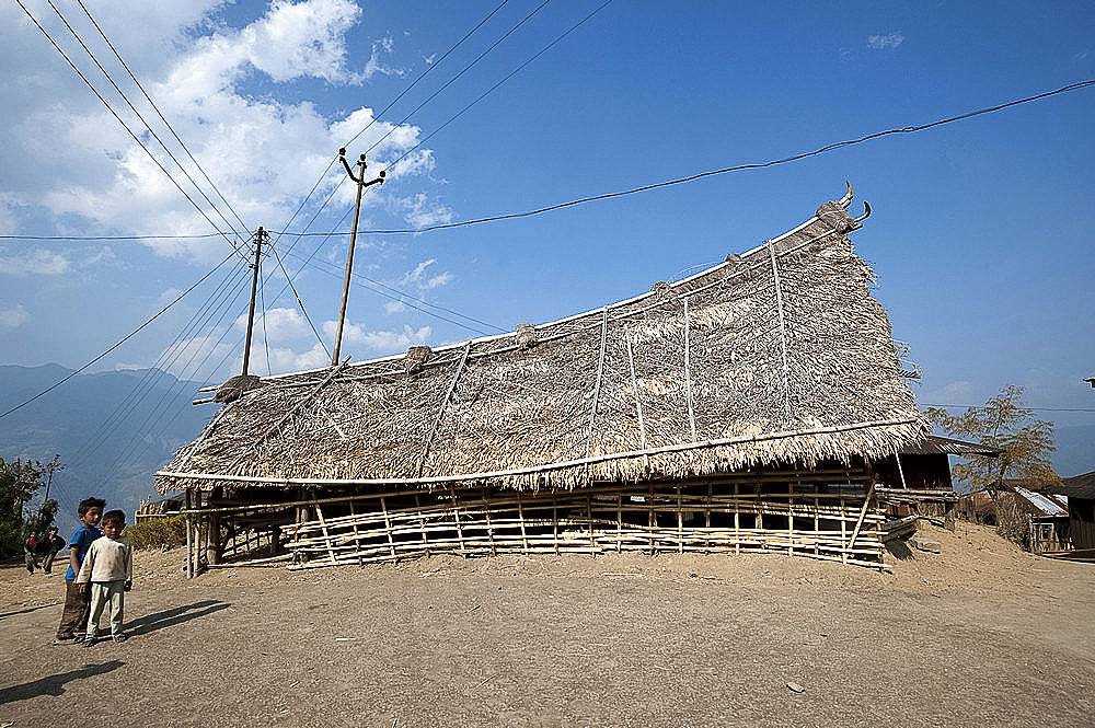 Naga children beside small bamboo constructed, fan palm thatched murung (meeting hall) with traditional curved roof, Nagaland, India, Asia