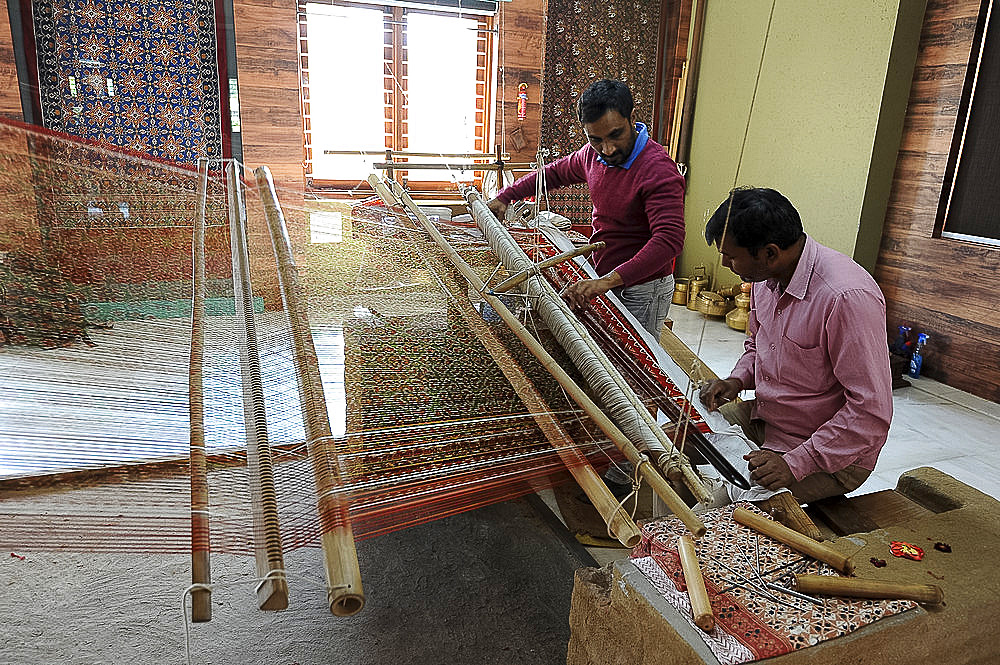 Two men working together to weave a complex double ikat Patola sari using a harness loom slanted to one side, Patan, Gujarat, India, Asia