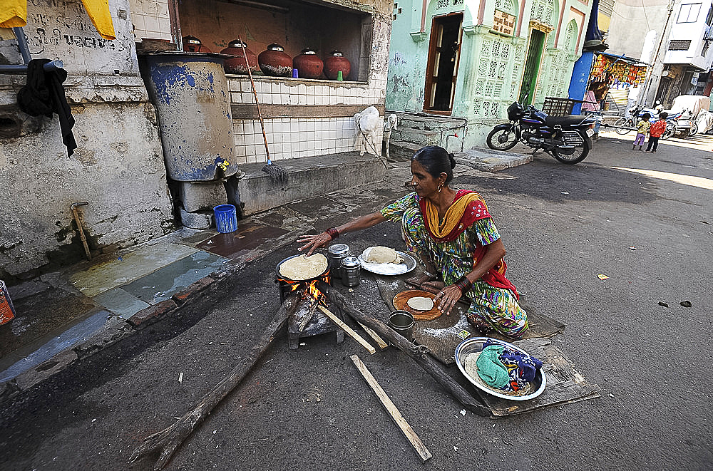 Woman making the day's chapatis on a wood fire in the street outside near the Jama Mosque in old Ahmedabad, Gujarat, India, Asia