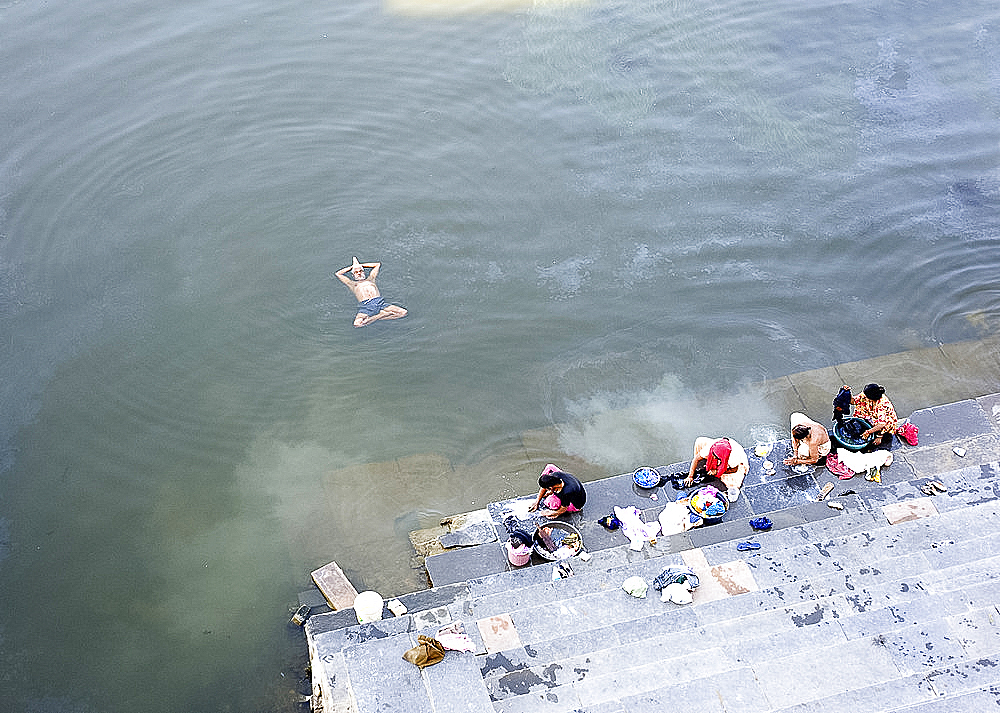 Man doing early morning yoga excercises in the water near the dhobi (washing) ghats, Lake Pichola, Udaipur, Rajasthan, India, Asia