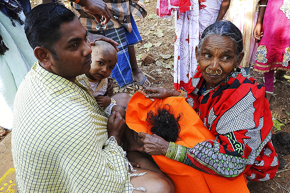 Mali tribeswoman holding hair of child having had her head shaved for choula, at the festival of Shivraatri, Koraput, Odisha, India, Asia