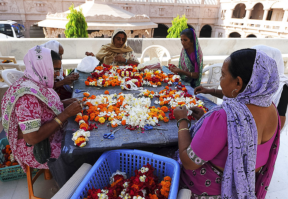 Women threading mala (garlands) for Diwali puja in the ornate white marble Swaminarayan Temple, Bhuj, Gujarat, India, Asia