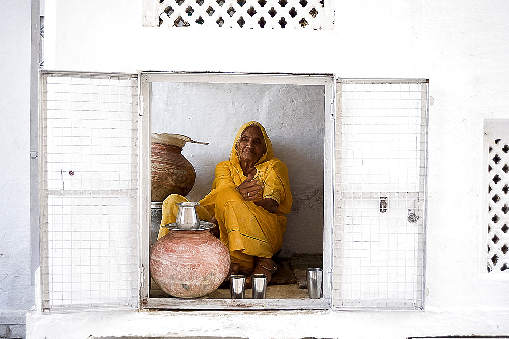 Woman offering drinking water to devotees at Jagdish temple, Udaipur, Rajasthan, India, Asia