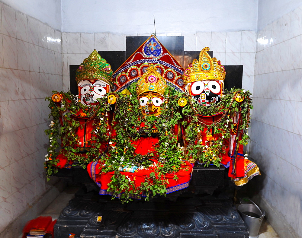 Trio of deities draped with leaf garlands inside temple to Lord Jagannath, rural Odisha, India, Asia