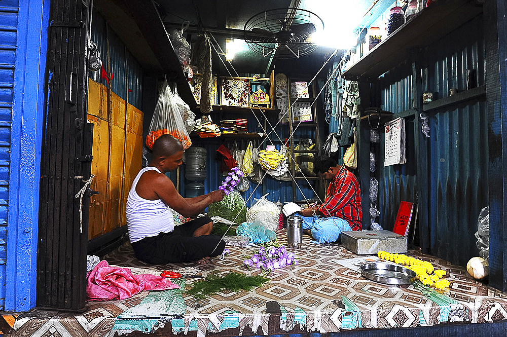 Two men in Malik Ghat flower market threading floral garlands, Kolkata, West Bengal, India, Asia