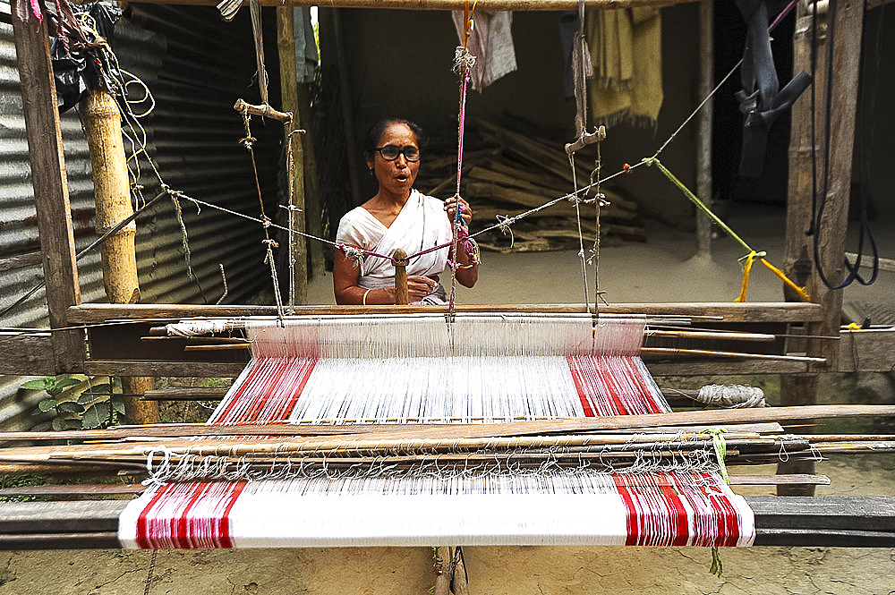 Village woman with domestic handloom, weaving a traditional Assamese cotton gamosa, white with red borders, Assam, India, Asia