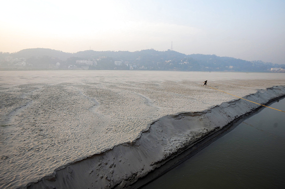 Pre-dawn cast off, man releasing ropes from a mooring in the fine sand of a seasonal sandspit in the Brahmaputra River, Assam, India, Asia