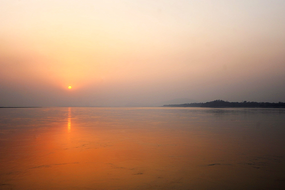 Sun setting over the vast waters of the mighty Brahmaputra River, Assam, India, Asia