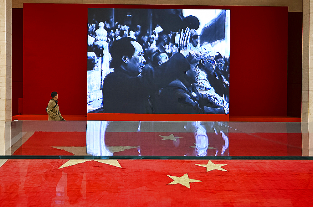 Museum visitor walking past party political slideshow in the National Museum of China, Beijing, China, Asia