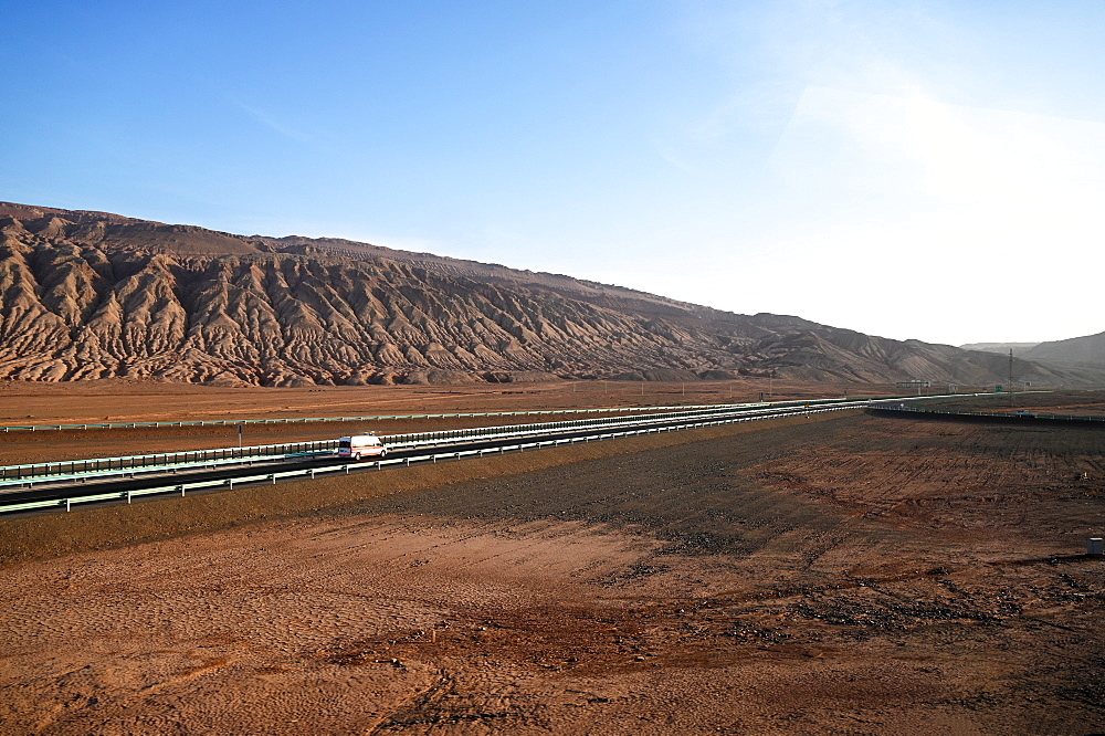 Police vehicle driving along the deserted Silk Road in the Gobi desert near Turfan, Xinjiang, China, Asia