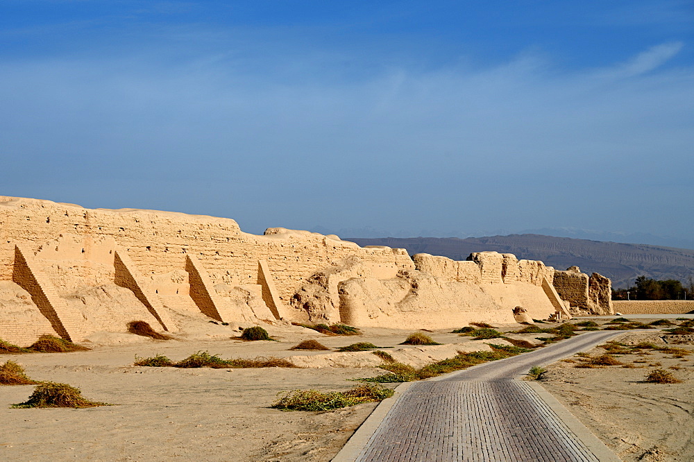 Road past ruined city wall of ancient Silk Road city of Gaochang, Taklamakan desert, Xinjiang, China, Asia