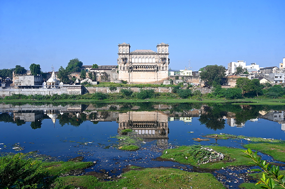 The 18th century Naulakha Palace facade reflected in the still waters of the Gondal River, Gondal, Gujarat, India, Asia