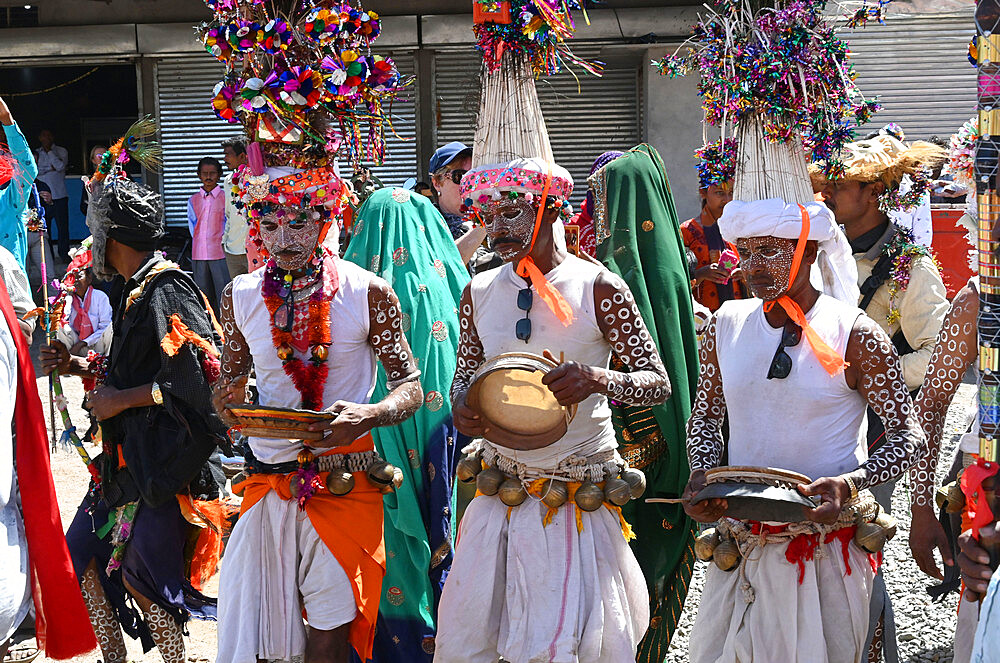 Adivasi tribal men, faces and bodies decorated, wearing ornate headgear, dancing to celebrate Holi festival, Kavant, Gujarat, India, Asia