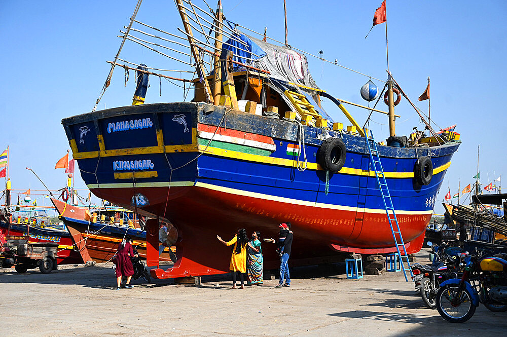 Family of boat owner performs puja on new boat by making hand prints along its hull prior to maiden launch, Vanakbara, Gujarat, India, Asia