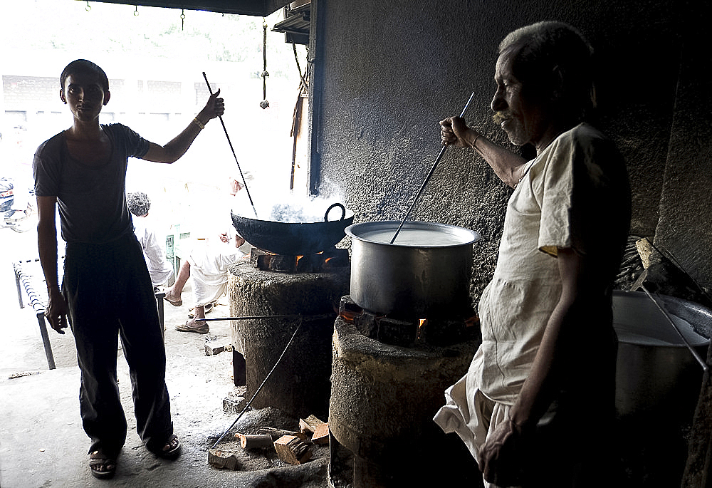 Young man and blind man stirring milk for chai, roadside chai stall, Dangiyawas, Rajasthan, India, Asia