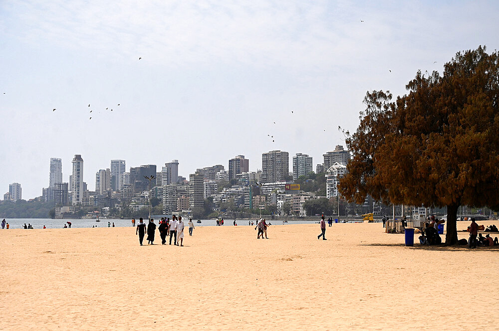 People strolling on Juhu beach, high rise city buildings in the background, Mumbai, India, Asia