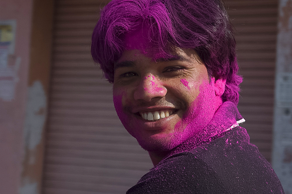 Young man playing Holi in the street with pink colour, Holi festival, Jaipur, Rajasthan, India