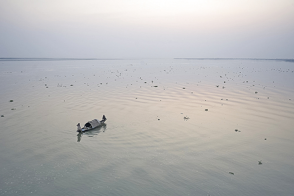 Two fisherman on boat at dawn on the Brahmaputra River, Assam, India, Asia