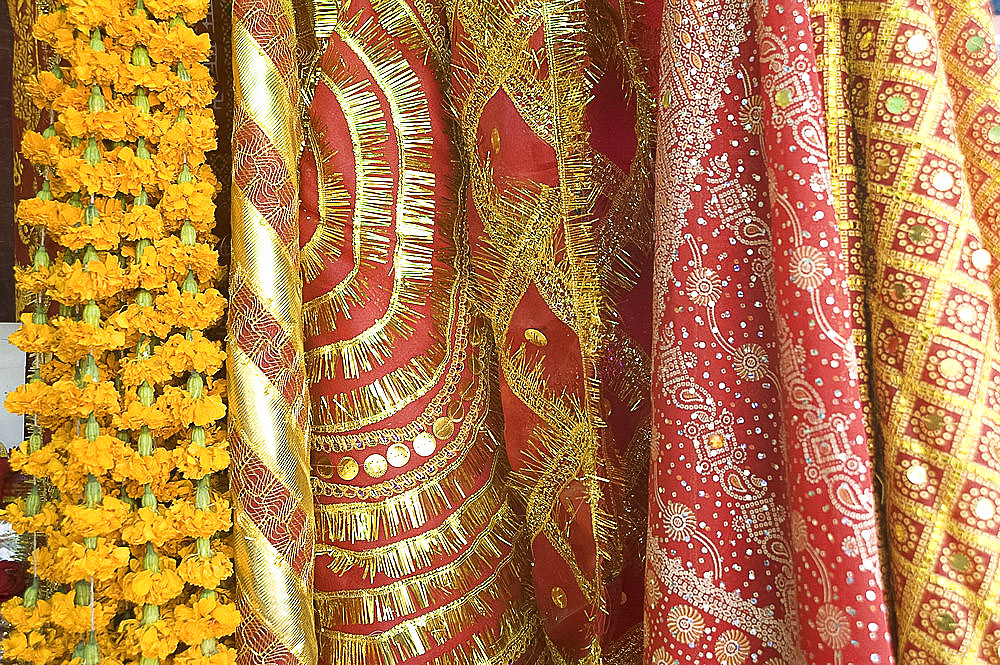 Red and gold tinselled cloths for Hindu devotees visiting a temple, and marigold flower garlands, Guwahati, Assam, India, Asia