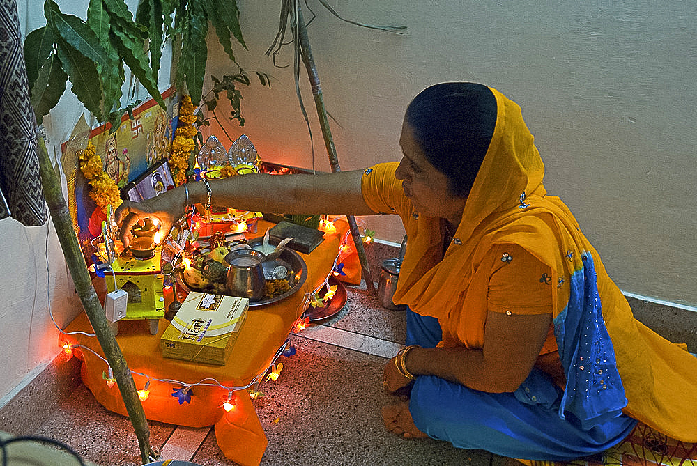 Sikh woman placing deepak light on domestic Diwali shrine, Jaipur, Rajasthan, India, Asia