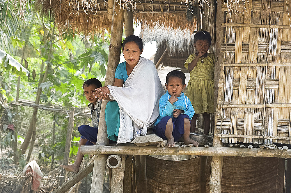 Mishing tribal family on the verandah of their family home, Majuli Island, Assam, India, Asia