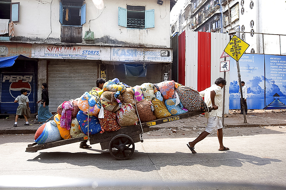 Laundrymen (dhobi wallahs), pulling wooden cart laden laundry from hotels for washing at Mahalaxmi dhobi ghats, Mumbai, India, Asia