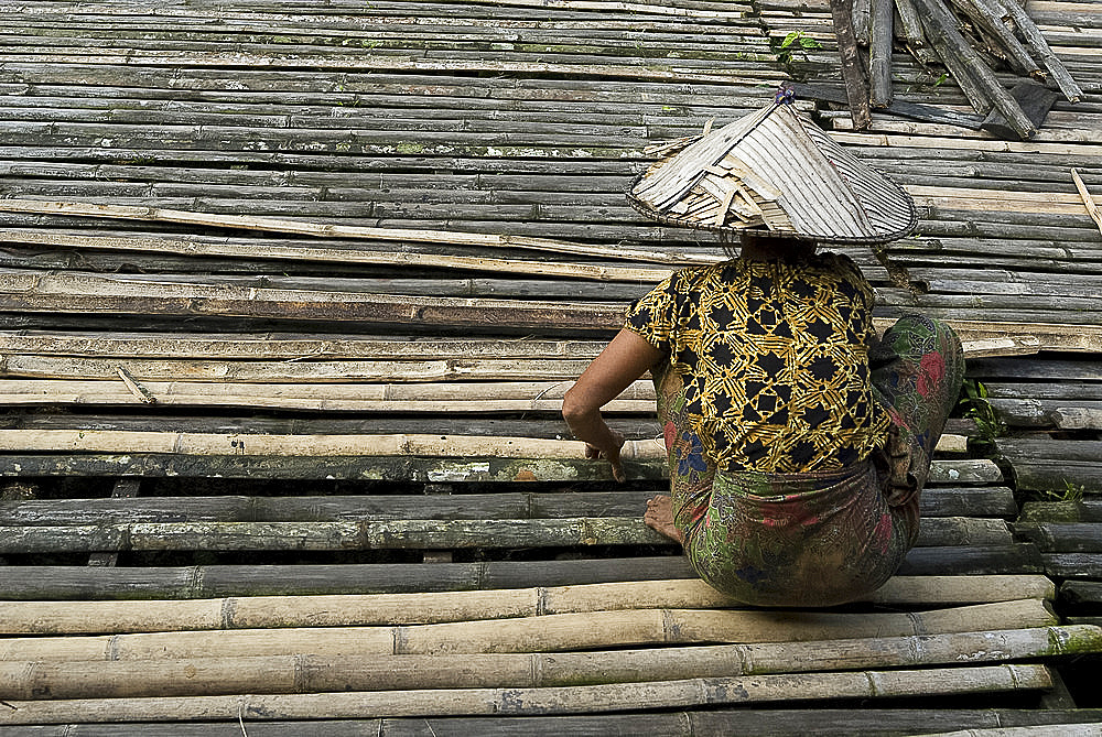 Iban tribeswoman mending bamboo longhouse verandah floor, Lemanak River, Sarawak, Malaysian Borneo, Malaysia, Southeast Asia, Asia