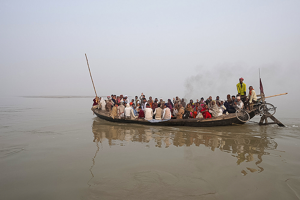 Ferry boat crossing the River Ganges in the early morning, carrying villagers and a bike strapped to the stern, Sonepur, Bihar, India, Asia