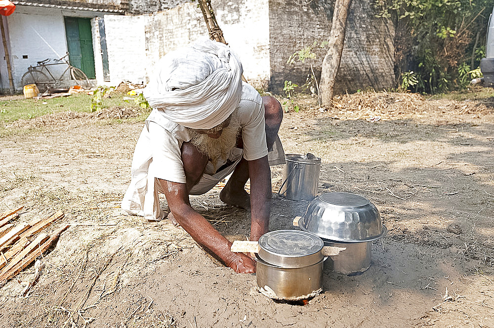 Bihari man in white turban and dhoti, making clay oven in the ground to cook his meal at Sonepur Cattle Fair, Bihar, India, Asia