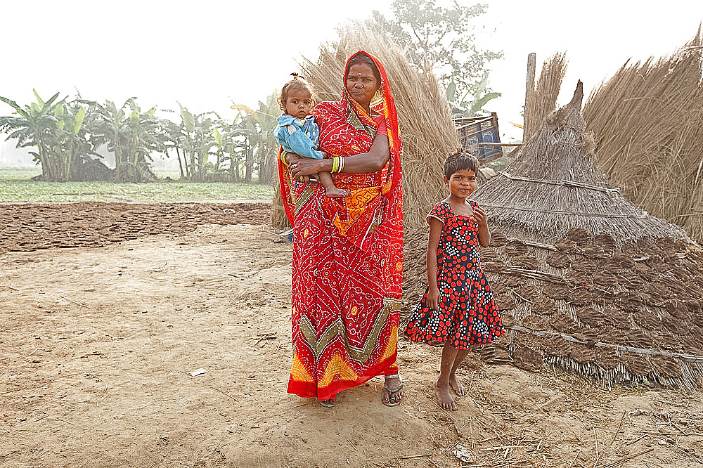 Mother in red sari and her two children in rural Bihari village at dawn, Sonepur, Bihar, India, Asia