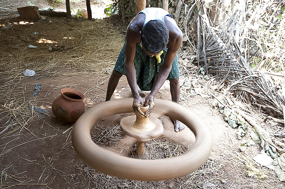 Village potter forming hand made clay pot on potter's wheel spinning in his village workshop, near Rayagada, Orissa, India, Asia