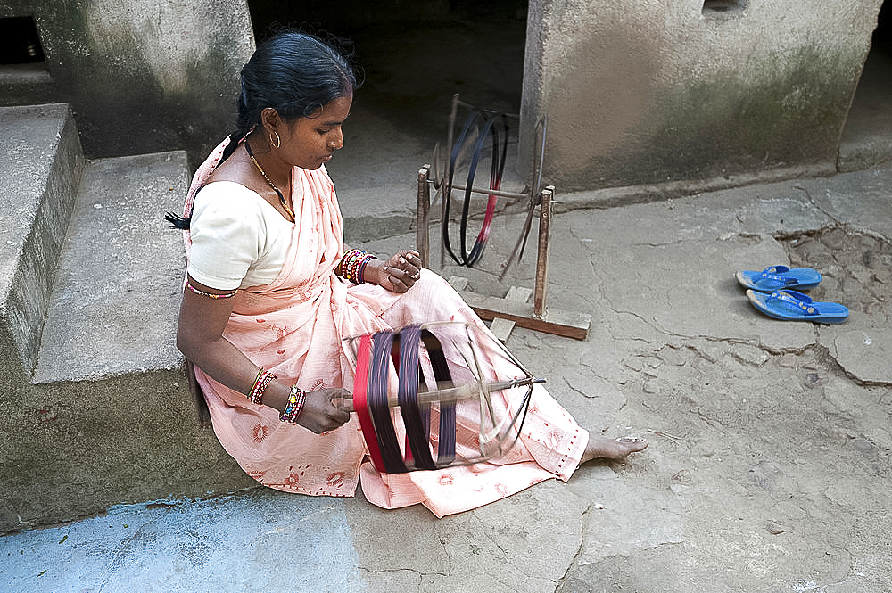 Woman spinning silk thread by hand outside her house, Vaidyanathpur, Orissa, India, Asia