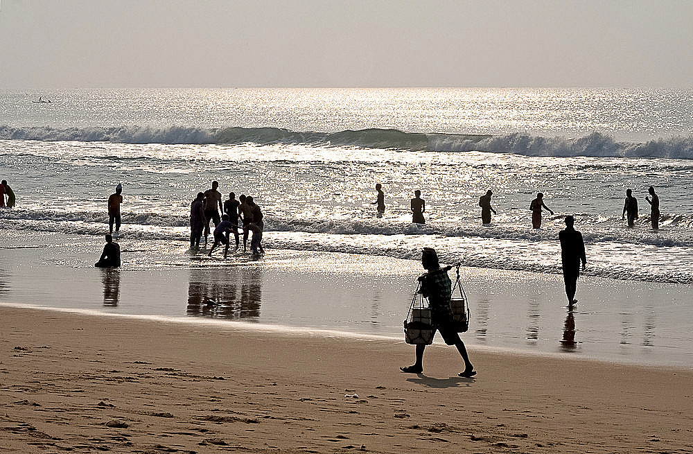 Puri beach on the Bay of Bengal, Indian families relaxing and paddling, beach vendor walking by in the late afternoon, Puri, Orissa, India, Asia