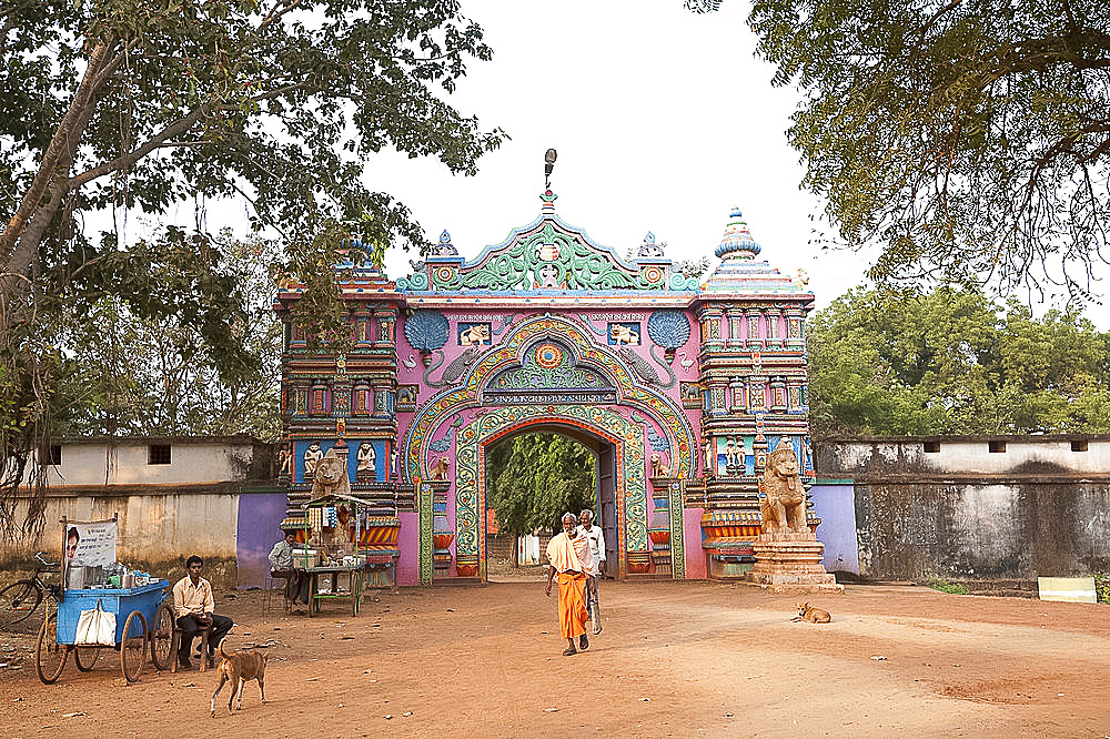 Ascetics walking through ornately carved and painted entrance to Joranda monastery complex, Joranda, Orissa, India, Asia