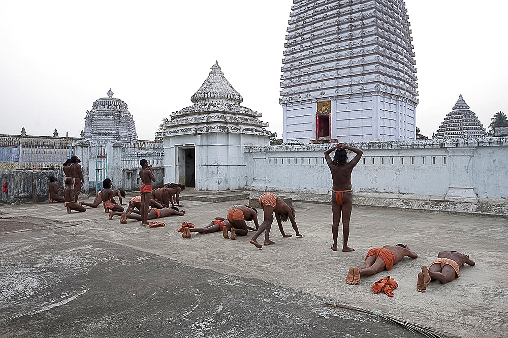 Joranda monks performing obeisance in prayer at temple containing a dhuni, an eternal butter lamp, at dusk, Joranda, Orissa, India, Asia