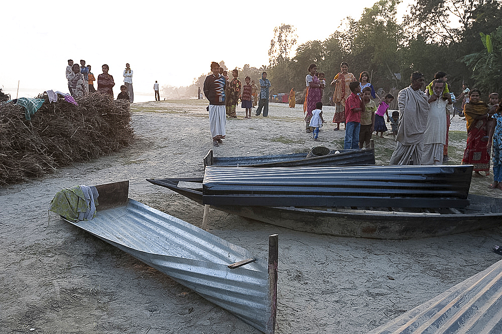 Villagers surrounding small boats made from single sheets of corrugated iron, lying on the banks of the River Hugli (River Hooghly), West Bengal, India, Asia