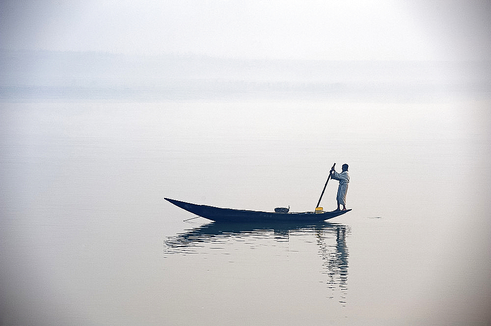 Man punting wooden boat along River Hugli (River Hooghly) at dawn, West Bengal, India, Asia