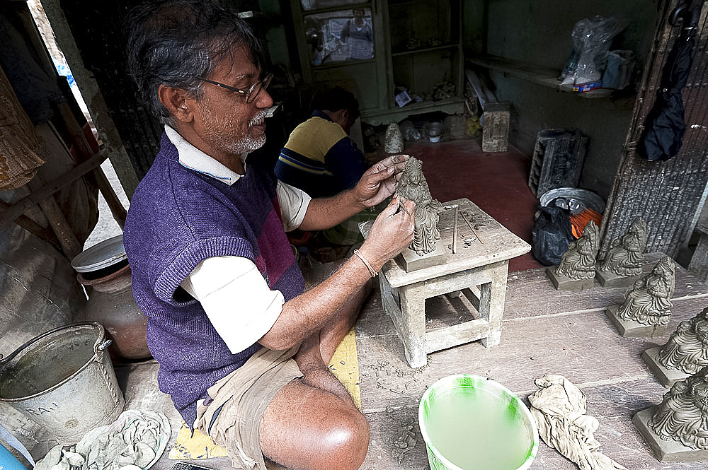 Master sculptor making models from clay from the River Hugli, to be painted for festival ceremonies, Kumartuli district, Kolkata, West Bengal, India, Asia