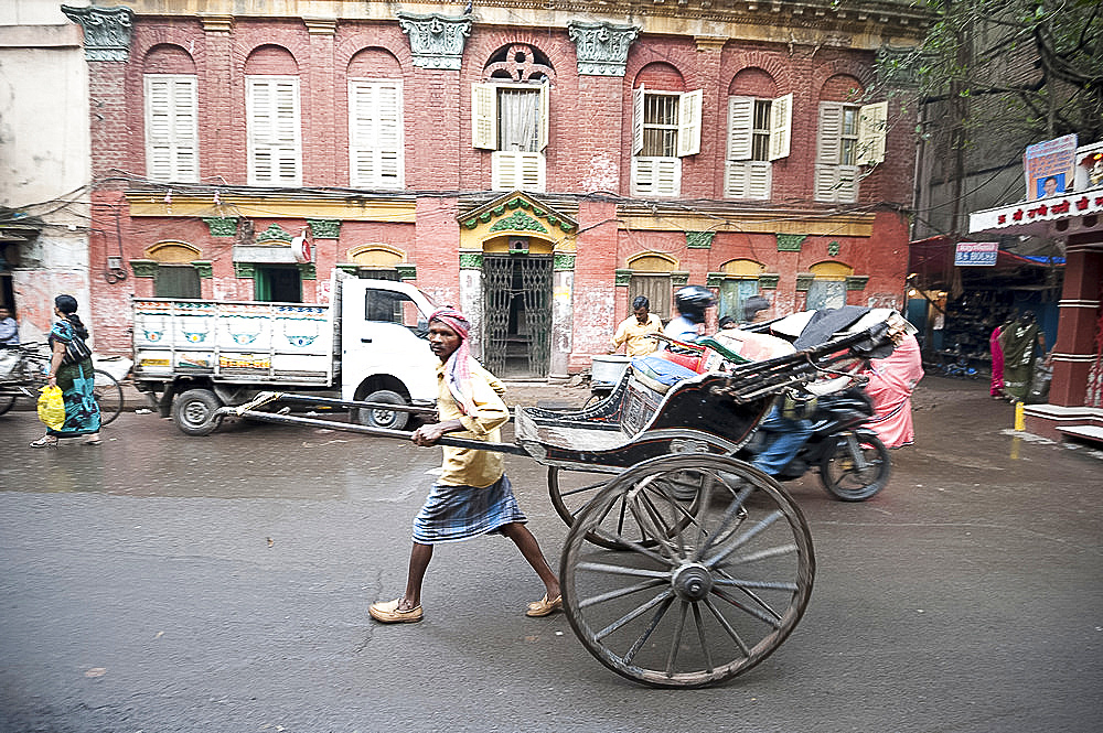 Running rickshaw wallah outside beautiful old Raj era Kolkata building in Kolkata backstreet, West Bengal, India, Asia