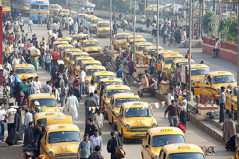 Yellow Kolkata taxis and commuters outside Howrah Railway Station in morning rush hour, Howrah, Kolkata (Calcutta), West Bengal, India, Asia