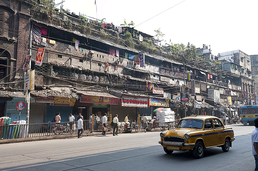 Yellow Kolkata taxi passing Kolkata slums in the early morning, Kolkata, West Bengal, India, Asia