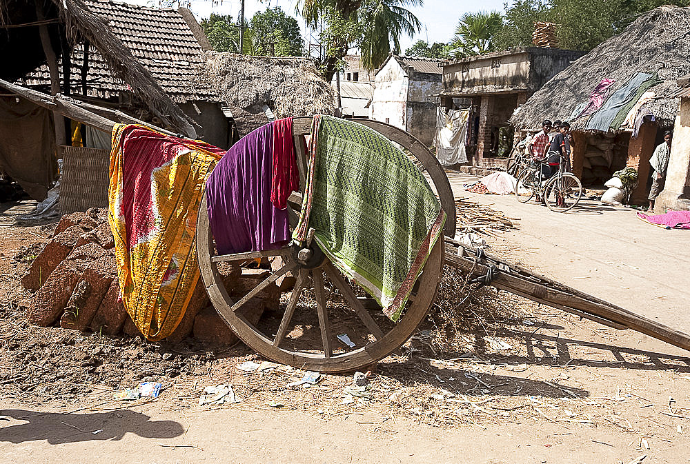 Washing drying over wooden cart wheel of wooden handcart in the street, Naupatana weaving village, rural Orissa, India, Asia