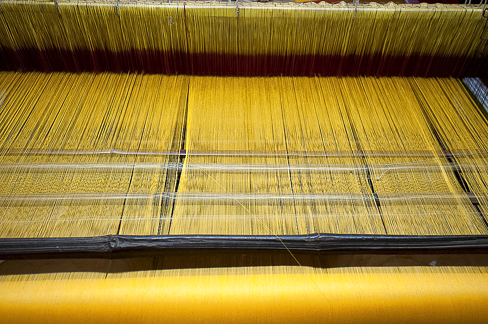 Yellow dyed silk being woven on loom, Naupatana weaving village, rural Orissa, India, Asia